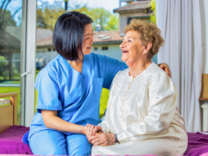 Healthcare professional laughing with patient on bed