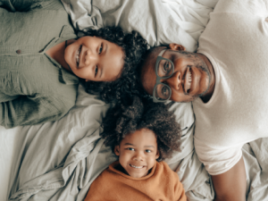 Padre con dos hijos acostados en la cama sonriendo