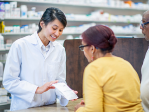 Smiling pharmacist showing prescription to two people