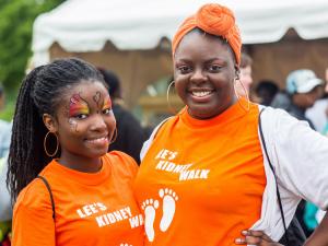 Two people posing with orange "Let's Kidney Walk" t-shirts