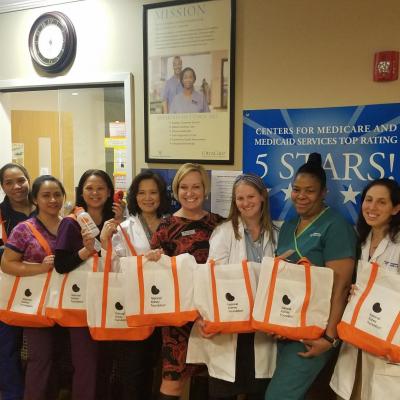 A group of healthcare professionals in scrubs holding national kidney foundation tote bags