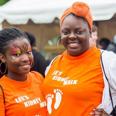 Two people posing with orange "Let's Kidney Walk" t-shirts