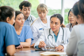 Group of doctors around table discussing.