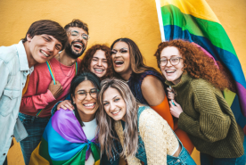 Group of happy LGBTQIA+ individuals hugging and smiling