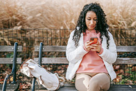 Mujer enviando mensajes de texto seriamente en un banco