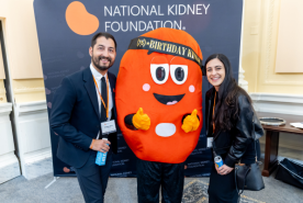 Two happy advocates on either side of kidney mascot