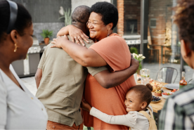 Two adults and child hugging and smiling