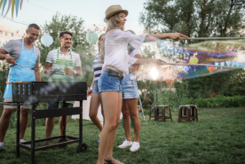 Person playing with bubbles next to people grilling