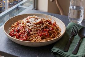 Whole wheat pasta with marinara sauce and parmesan in a bowl on an elegant table