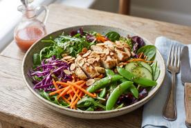 Mixed greens salad with fresh vegetables, nuts, chicken, and a strawberry vinaigrette