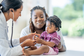 Mother holding baby grabbing doctor's stethoscope