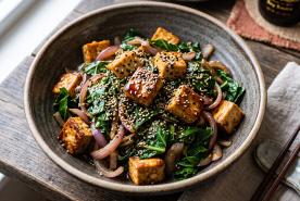 Sautéed collard greens with tofu and onions, topped with sesame seeds