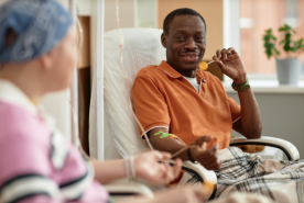 Person eating lollipop on dialysis speaking to another patient