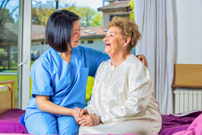 Healthcare professional laughing with patient on bed
