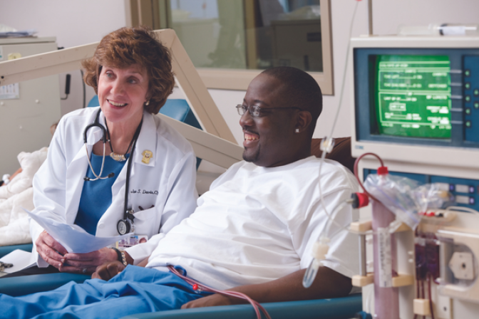 Doctor sitting with smiling dialysis patient