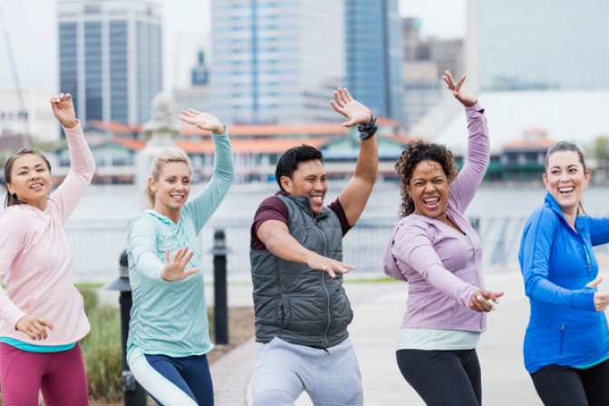 Group of people smiling and exercise dancing outside