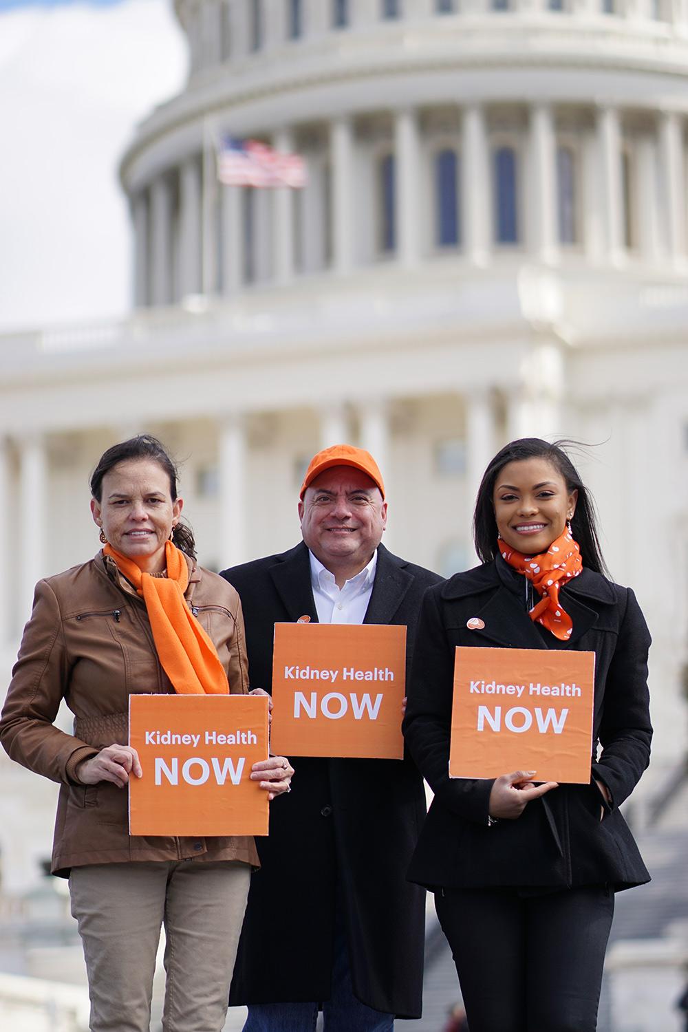 Three advocates holding "Kidney Health NOW" signs