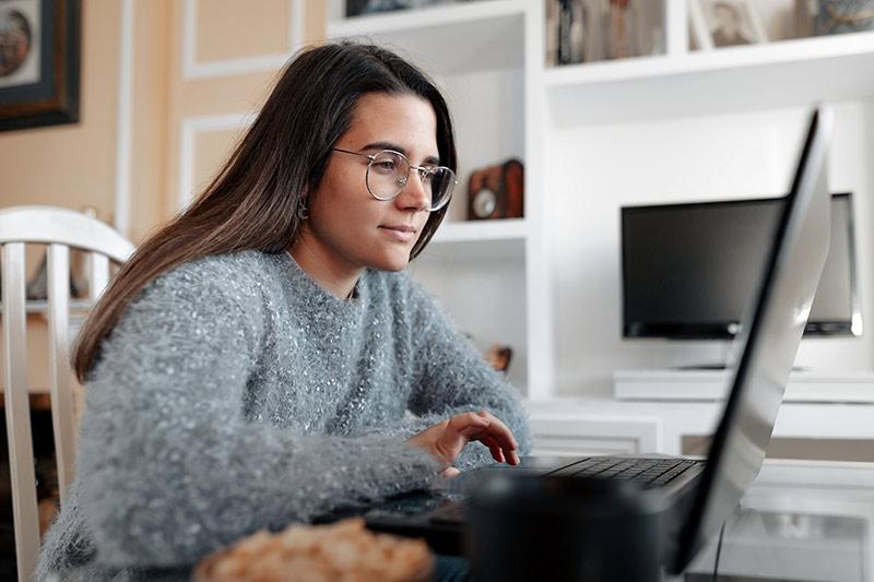 Woman looking at a laptop at her home desk