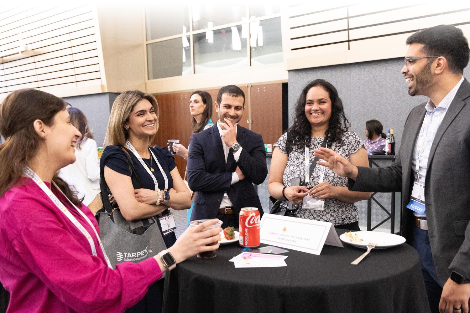 Attendees standing around a table at a reception and chatting