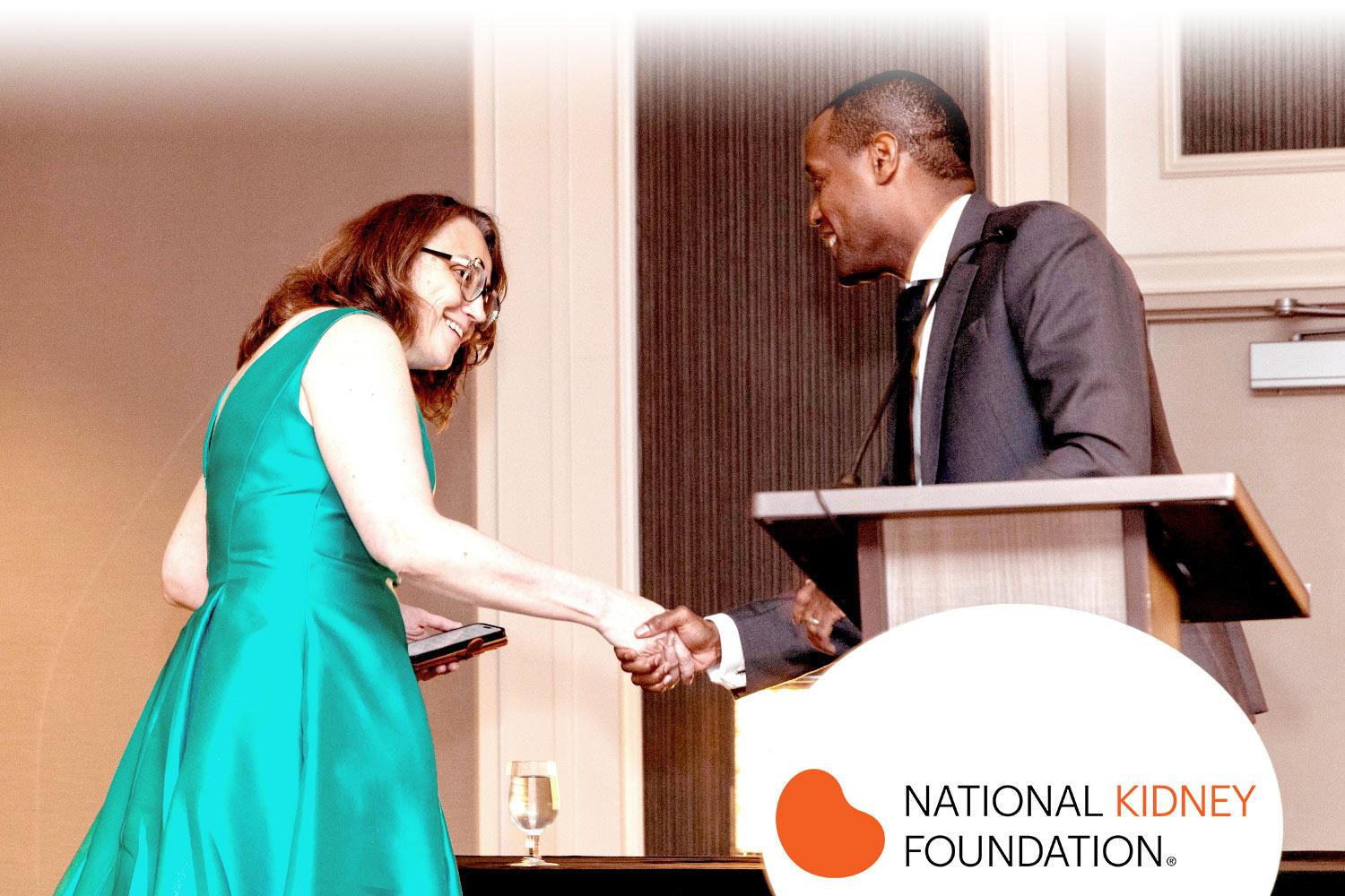 NKF's Board President shaking hands with an award recipient on stage