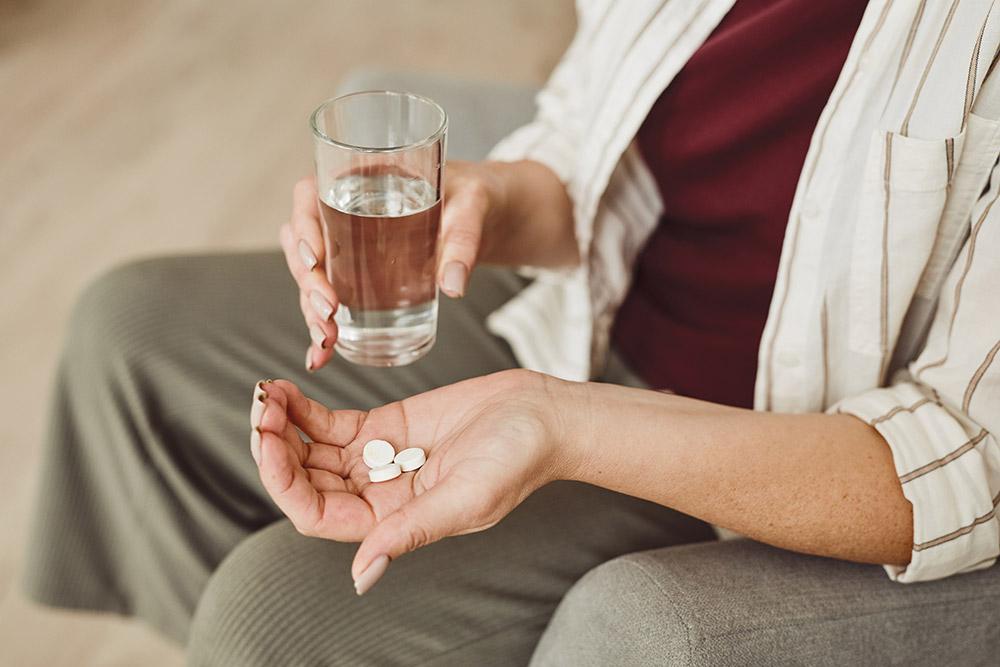Adult holding pills and water in their hands