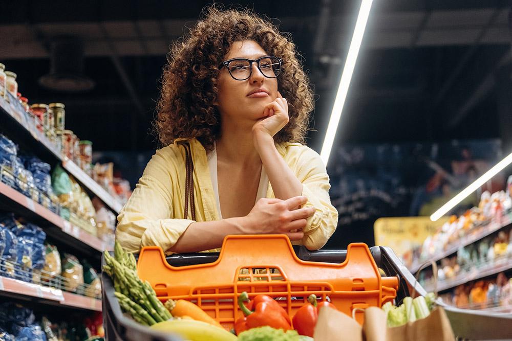 Thoughtful woman with groceries in a supermarket