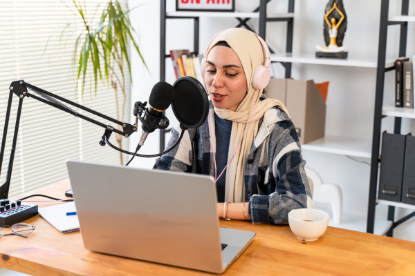 Person in hijab speaking into microphone at desk