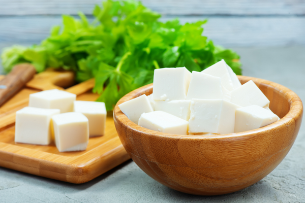 Tazón de tofu cortado cerca de las verduras