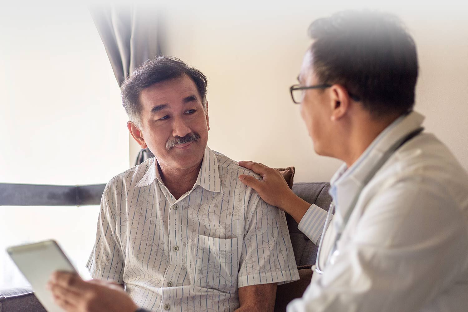 Doctor talking with elderly Asian patient