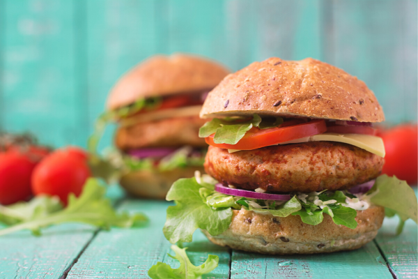 Two juicy turkey burgers with lettuce and tomato.