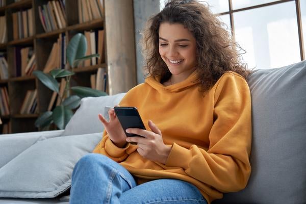 woman dialing phone number while sitting on the couch